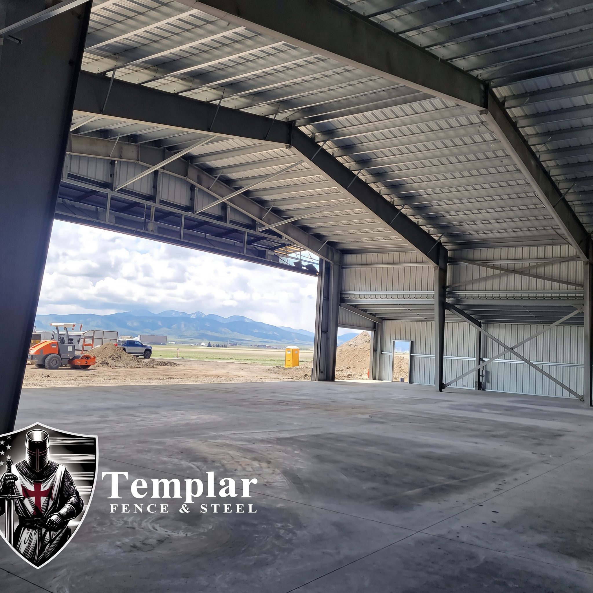 Interior of a large steel hangar with an open door bay